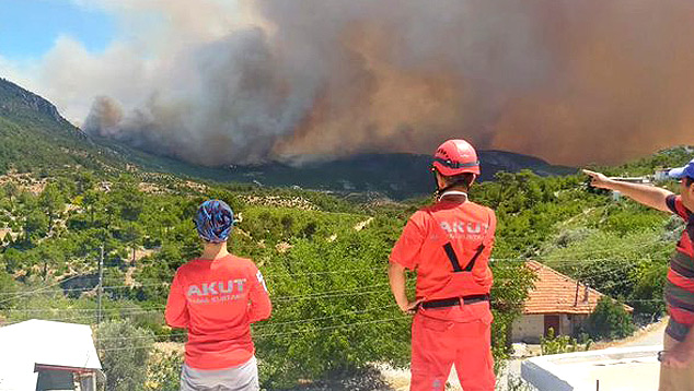 Voluntários no combate aos incêndios na Turquia observam um dos focos, de dezenas, que se alastraram na costa sul nos últimos dias. Crédito: Imagem divulgada pelo twitter @AKUTASSOCIATION